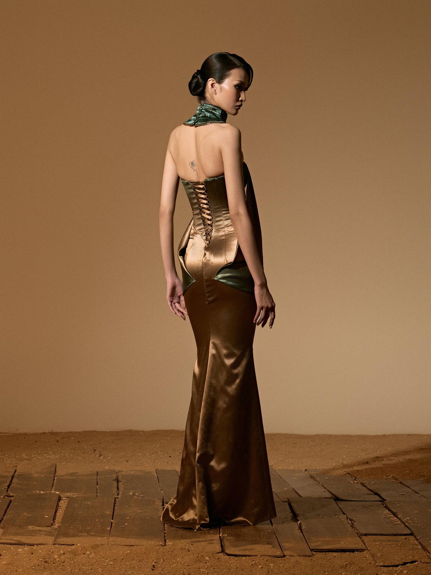 Woman in a long, elegant dress with a backless design on a beige background