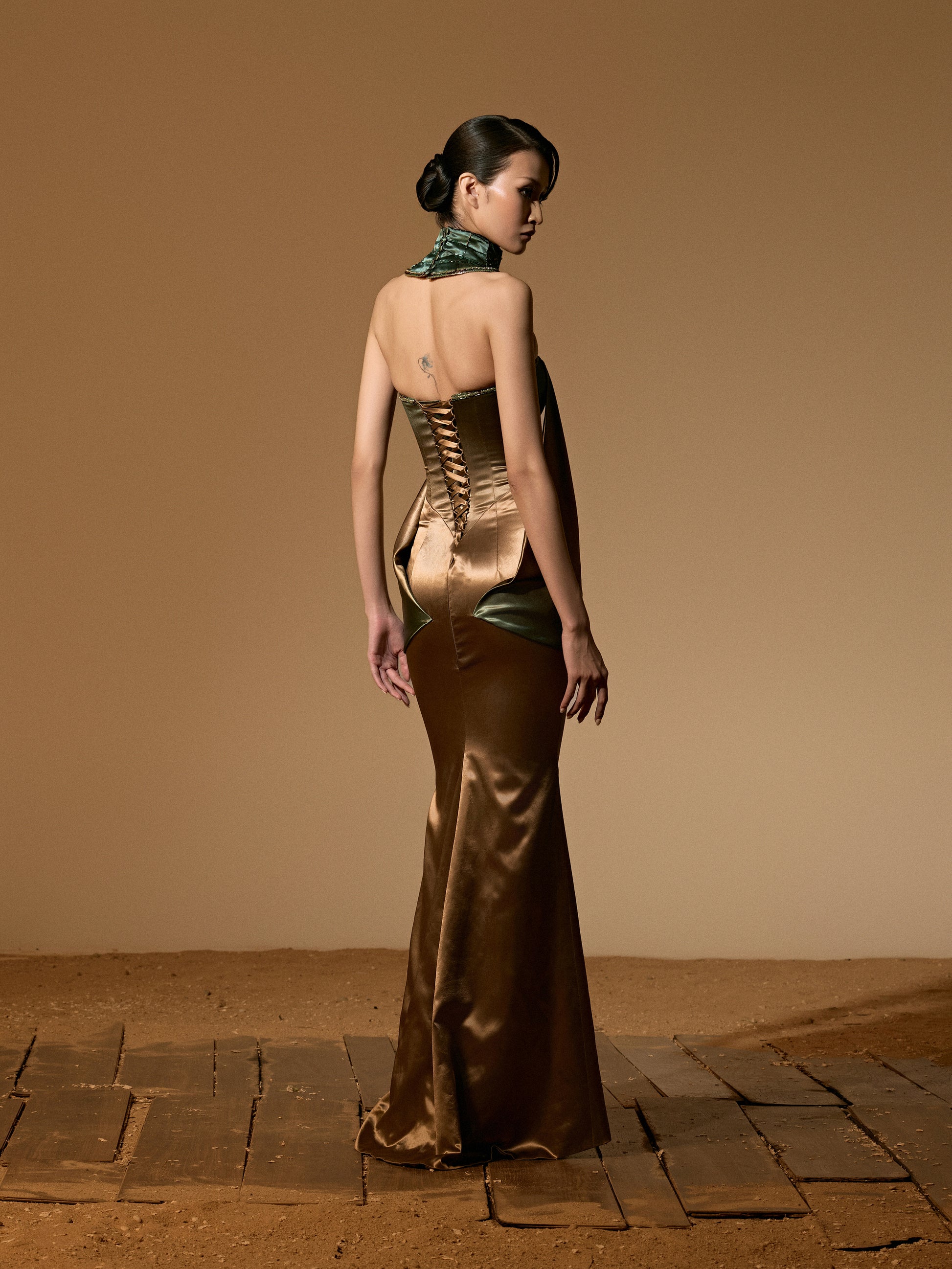 Woman in a long, elegant dress with a backless design on a beige background